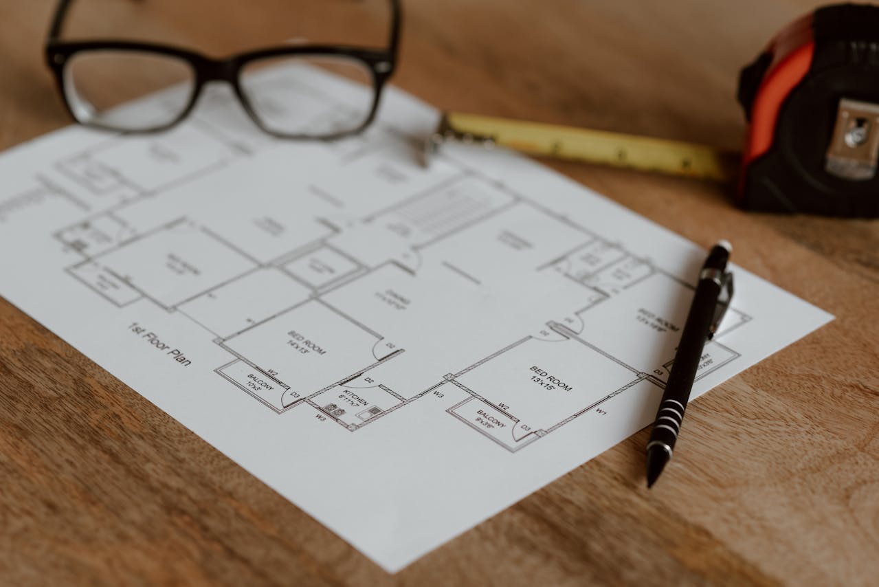 House plan with glasses, tape measure, and pen on a flat surface